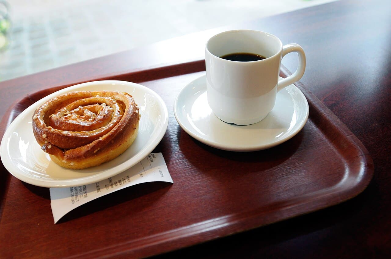 Bricka med kaffekopp och kanelbulle.